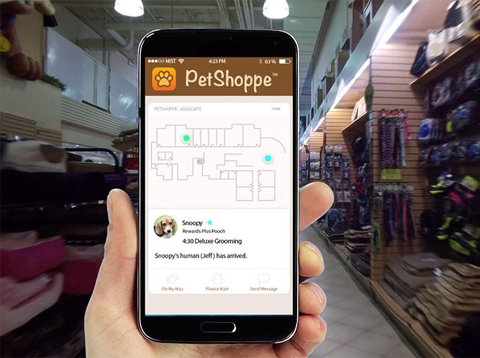 Person holding a smartphone displaying a PetShoppe application with location services in a store.